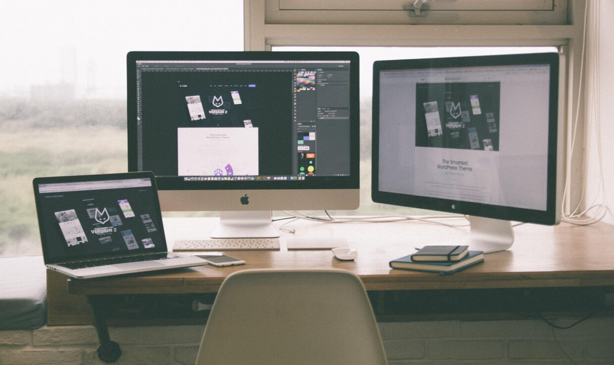 Multi-monitor workstation with design tools open, planning system architecture and UI components for a scalable product